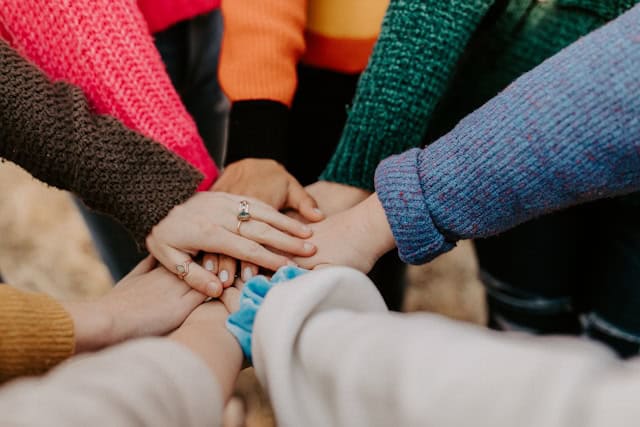 viele Personen halten die Hände aufeinander